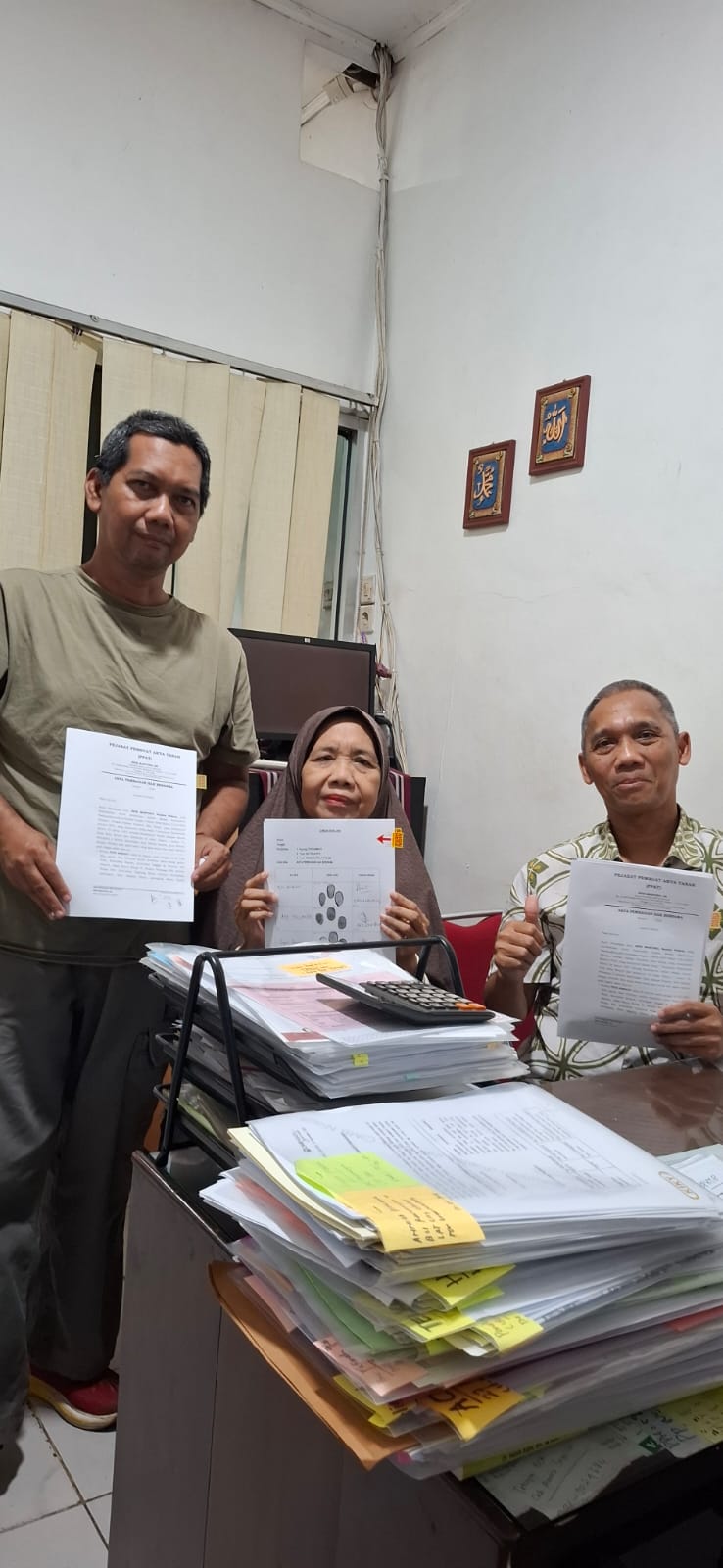 Tim Solusi Tanah bersama klien memegang dokumen sertifikat tanah